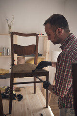 Man working in a small home workshop for furniture repairing and restoration.