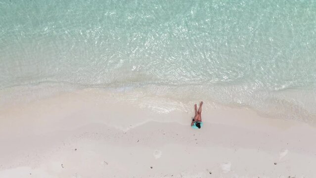 Frau sitzt am Strand einer Insel auf den Malediven. Woman sitting on the beach of an island in the Maldives