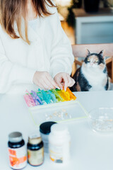 Woman sorting pills into pills organizer with her cat on the kitchen. Pill box with daily doses of medicines. Antioxidant diet vitamin supplements for health and beauty care, biohacking concept.