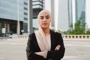 Young muslim business woman wearing hijab and looking serious on camera outside of office building