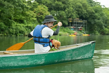 Foto op Canvas 飼い犬と一緒にカヤックで川下りを楽しむ男性 © One