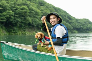 飼い犬と一緒にカヤックで川下りを楽しむ男性