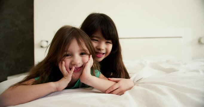 Two happy small kids in bedroom, smiling and looking to the camera