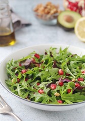 A plate with green rocket salad with pomegranate	