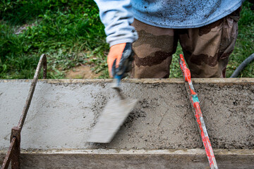 Bricklayer spreading concrete with a trowel and level to build a wall at a construction site