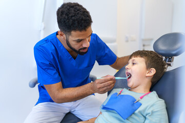 Obraz premium Liitle boy sitting on a dentists chair during dentist examination.