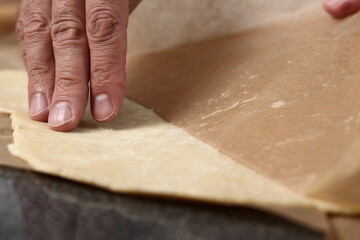 Chef removing baking paper from dough sheet
