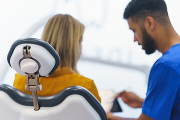 Obraz premium Rear view of multiracial dentist and patient sitting in a dentists chair.