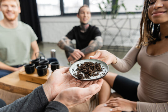 Smiling African American Woman Passing Plate With Fermented Puer Tea To Man In Yoga Studio.