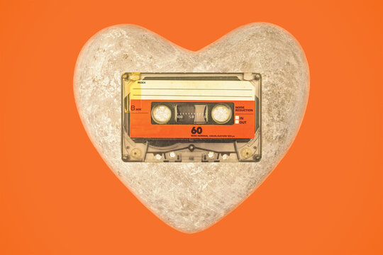 Vintage audio compact cassette with heart on an orange background