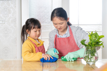 Fototapeta premium The little girl and her mother are cleaning at home together