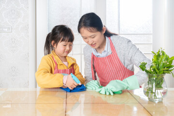 Fototapeta premium The little girl and her mother are cleaning at home together