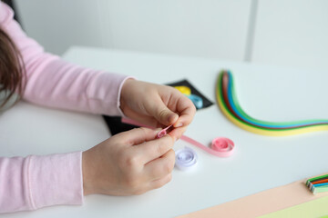 Children's activities, hands with paper top view, quilling technology