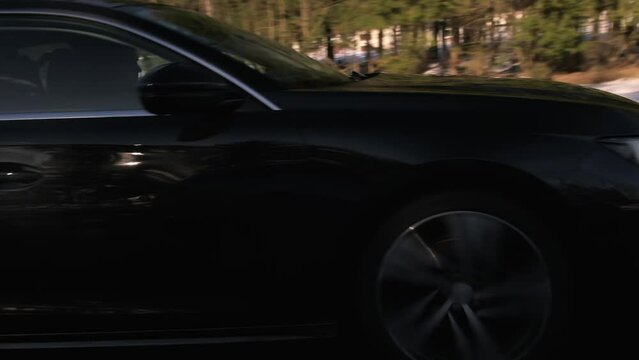 black car driving on the road in sunny weather, early spring, slow motion