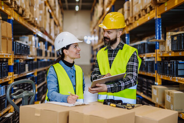 Warehouse workers checking stuff in warehouse with digital system in tablet, holding solar panel.