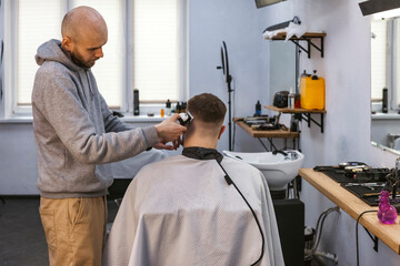 A hairdresser or barber is working with a shaving machine on the hair.