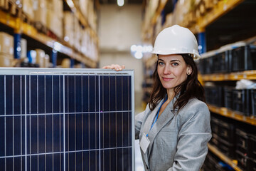 Portrait of manager holding a solar panel in a warehouse.