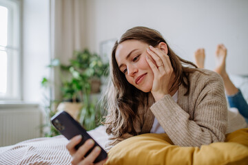 Young woman scrolling her smartphone in the apartment.
