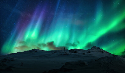 Fototapeta na wymiar Aurora borealis over silhouette cheerful man on top of mountain in arctic circle at Norway