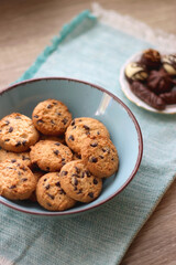 Plate of chocolate pralines, bowl of cookies, cups of tea, glasses of juice and lit candles on the table. Selective focus.