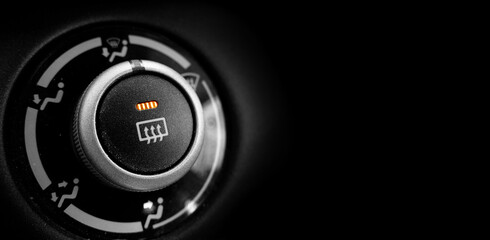 Defrost Button in Car With Orange Light On Black Background