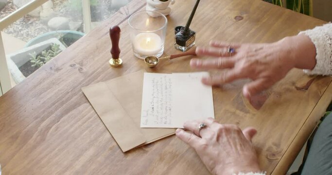 Folding a handwritten letter and inserting it into a vintage envelope to mail to a friend.