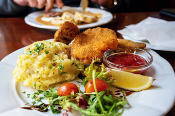 Fried schnitzel, mashed potato, green leaf, tomato and cranberry marmelade.