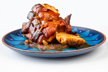 Baked pork belly and garlic on decorative blue plate.