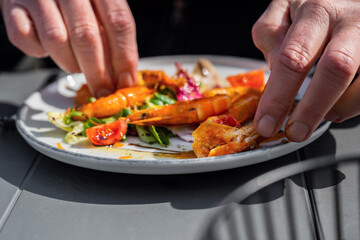 Hand of man peeling shrimp in plate.