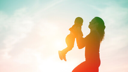 Mother encouraged her son outdoors at sunset, silhouette concept