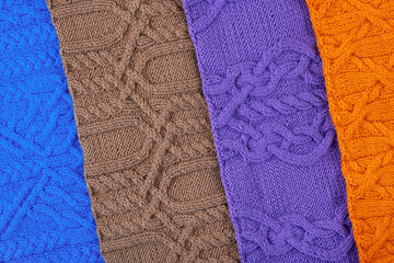Knitted blue, lilac, brown, and orange background. Large knitted fabric with a pattern. Close-up of a knitted blanket. Banner
