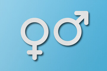 White paper cut into male and female symbol shapes. set on a light blue background