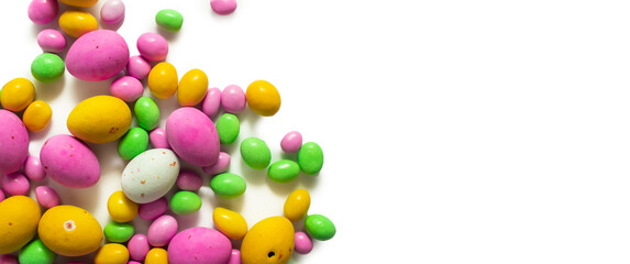 Banner of Colored dragees and chocolate eggs. Easter sweets closeup background