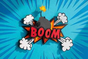 Handmade colorful paper cutting speech bubble with text boom. Pop art and comic style. Blue background. 