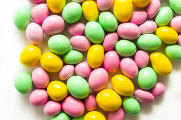 Colored dragees and chocolate eggs. Easter sweets closeup background