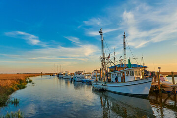 Fototapeta na wymiar Sunset with shrimp boats along a dock at Tybee Island, Ga.