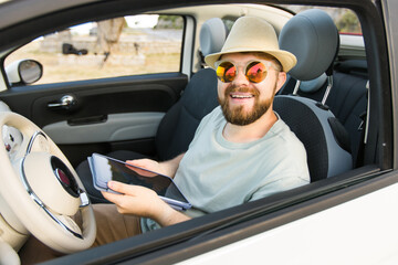Bearded man using digital tablet inside car while travel and road trip vacation holidays - road map and navigation concept