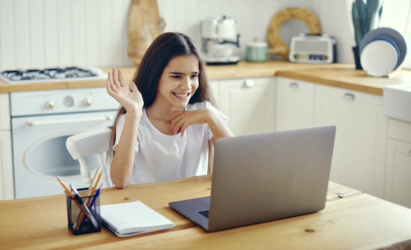 Pretty pre-teen girl using laptop greeting online tutor