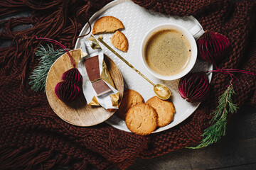 Cup of coffee with cookies on a tray and a knitted blanket.
