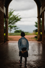 A boy walking in an atrium of a building heading outside in Uganda Africa