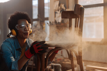 Wood worker blowing dust from chair.