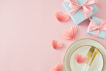 Mother's Day concept. Top view photo of circle plate cutlery knife fork gift boxes with bows and origami paper hearts on isolated pastel pink background with empty space