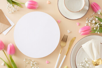 Mother's Day celebration concept. Top view photo of white circle cutlery knife fork plate fabric napkin cup and saucer colorful hearts and pink tulips on pastel beige background with blank space