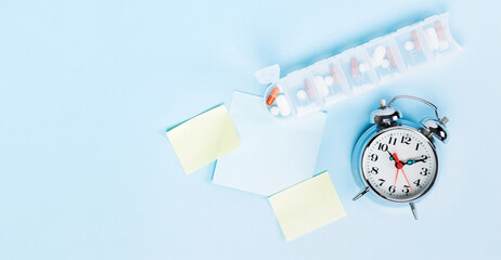 Medicine for daily intake by hour, capsules and tablets in white plastic pill box for week, note...