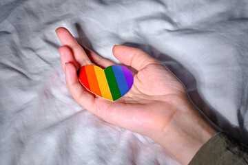 Rainbow heart from paper in woman hands. LGBT flag. LGBTQIA Pride Month in June. Lesbian Gay Bisexual Transgender. Gender equality. Human rights and tolerance. Rainbow flag
