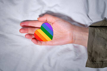 Rainbow heart from paper in woman hands. LGBT flag. LGBTQIA Pride Month in June. Lesbian Gay Bisexual Transgender. Gender equality. Human rights and tolerance. Rainbow flag