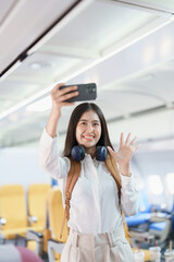 Asian business woman passenger sitting on business class luxury plane while working using smart phone mobile talking or video conference and travel concept