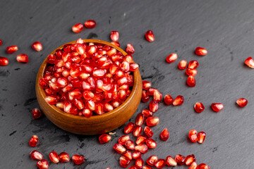 Red ripe pomegranate seeds with lots of juice in a wooden bowl