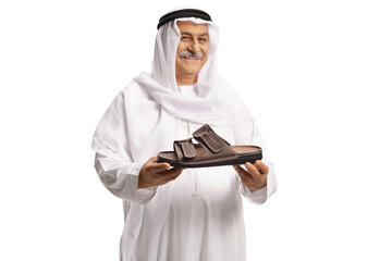 Arab man holding a brown leather sandal and smiling