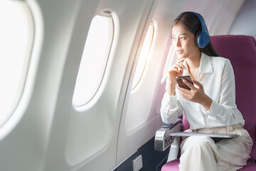 Young Asian attractive business woman passenger sitting on business class luxury plane while...